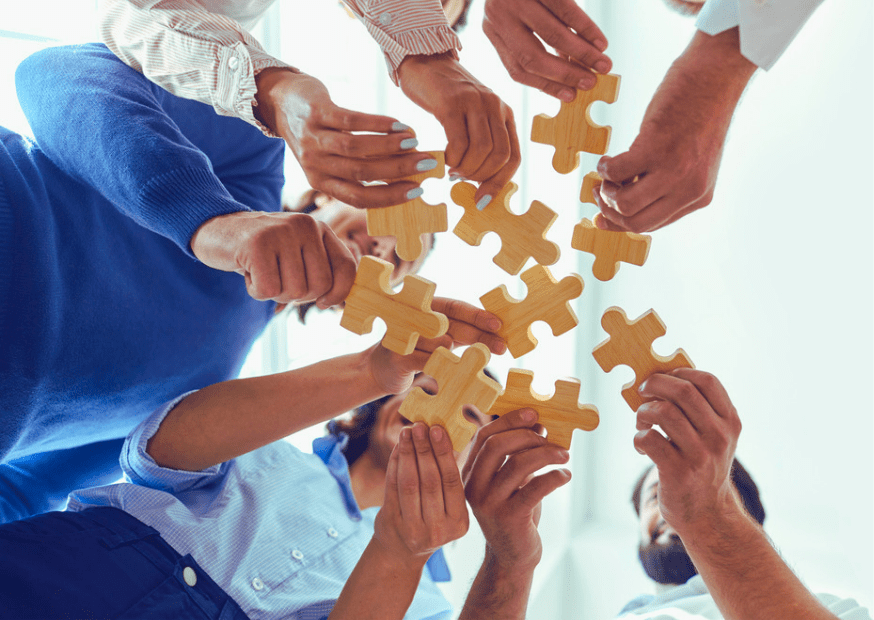 The Community of Practice team members are holding puzzle pieces as a symbol of teamwork and efficiency.
