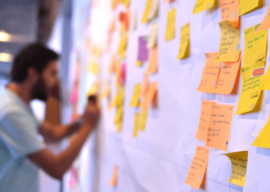 Team member actively participating in user story decomposition, organizing colorful sticky notes on a whiteboard for agile project management.